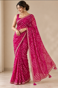 Model draped in a rani pink bandhani print georgette saree with a narrow gold lace border and magenta tassel pallu