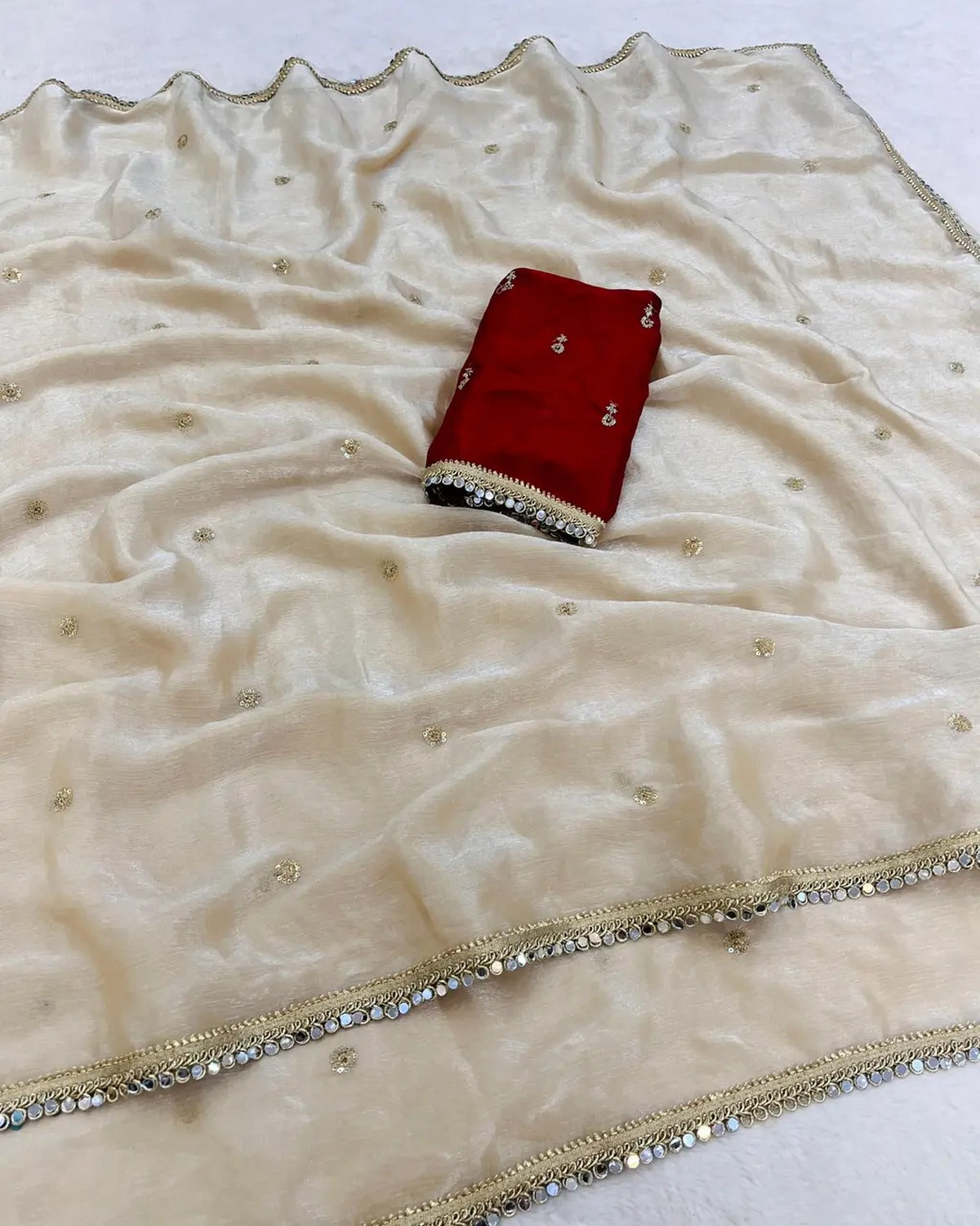 Ivory shimmer chiffon saree with gold sequin motifs, mirror lace border and red embroidered blouse piece