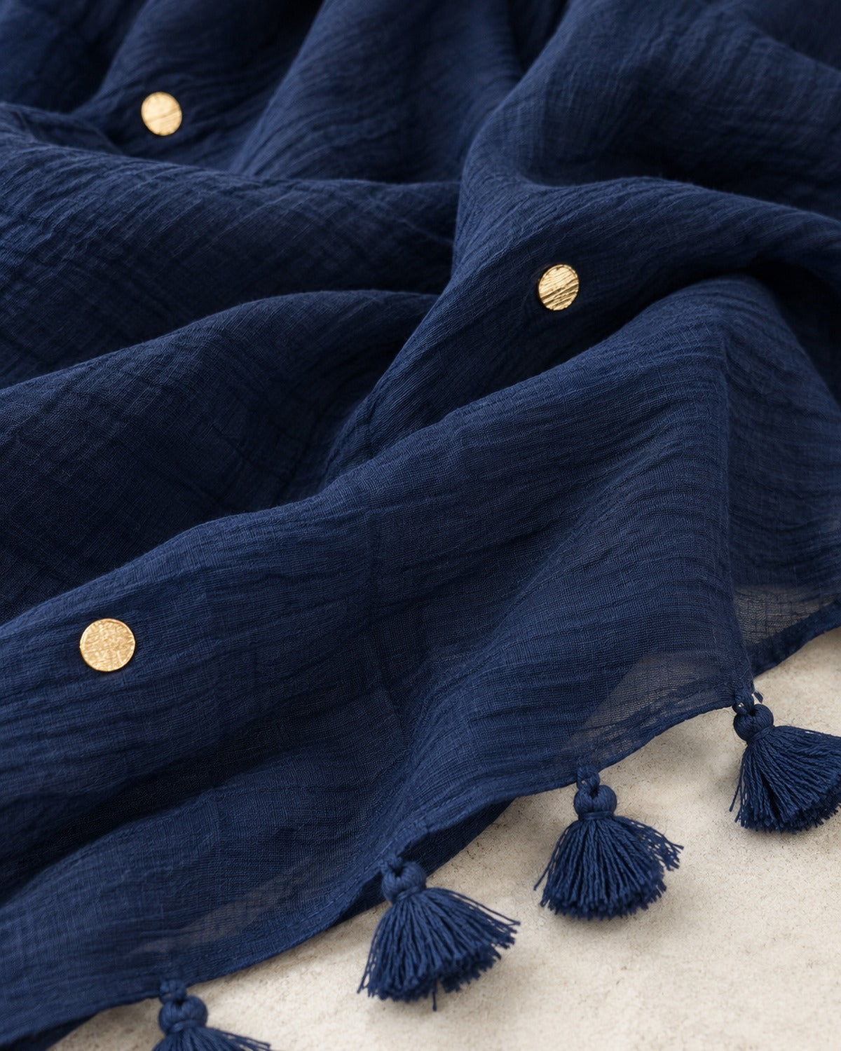 Close detail of the navy crushed cotton texture, gold studs and tassel border