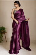 Model draped in a plain deep plum satin silk saree with a glossy sheen, styled with a silver shimmer blouse