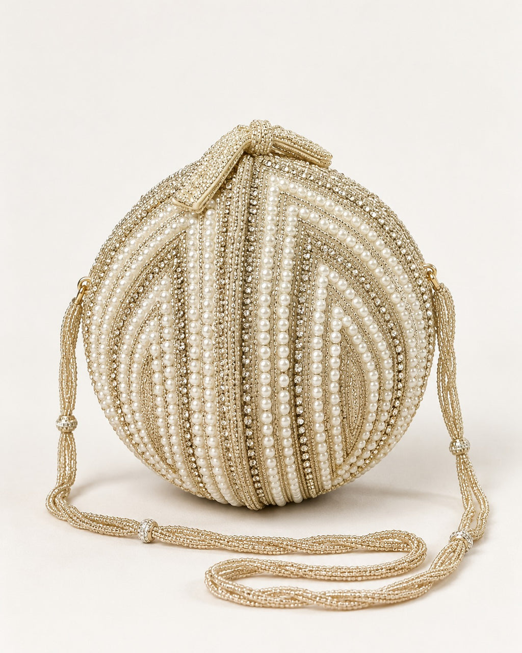 Pearl shell potli clutch with gold beaded chain sling on a plain off-white background