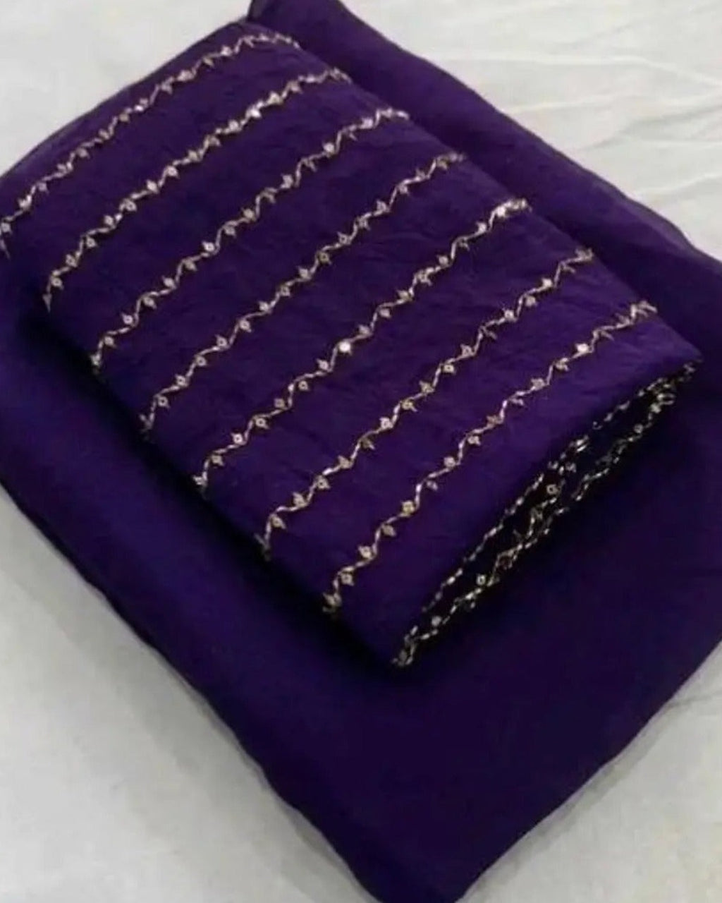 Deep purple crush saree with gold zari stripes, folded with blouse piece