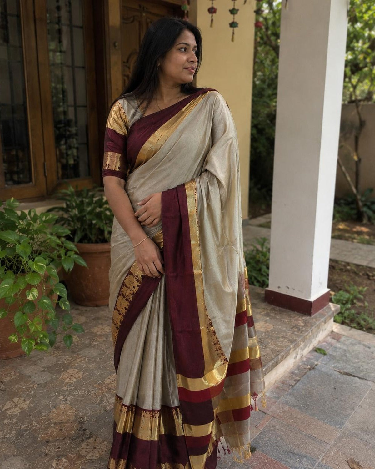 Beige cotton silk saree with maroon and gold zari border, worn
