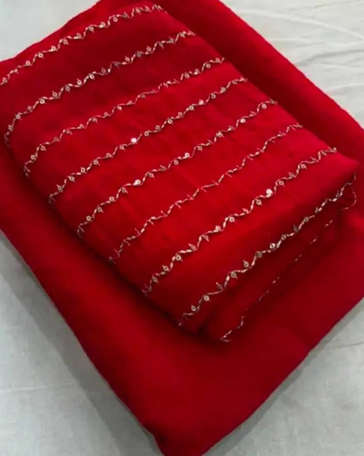 Red crush saree with gold zari stripes, folded with blouse piece