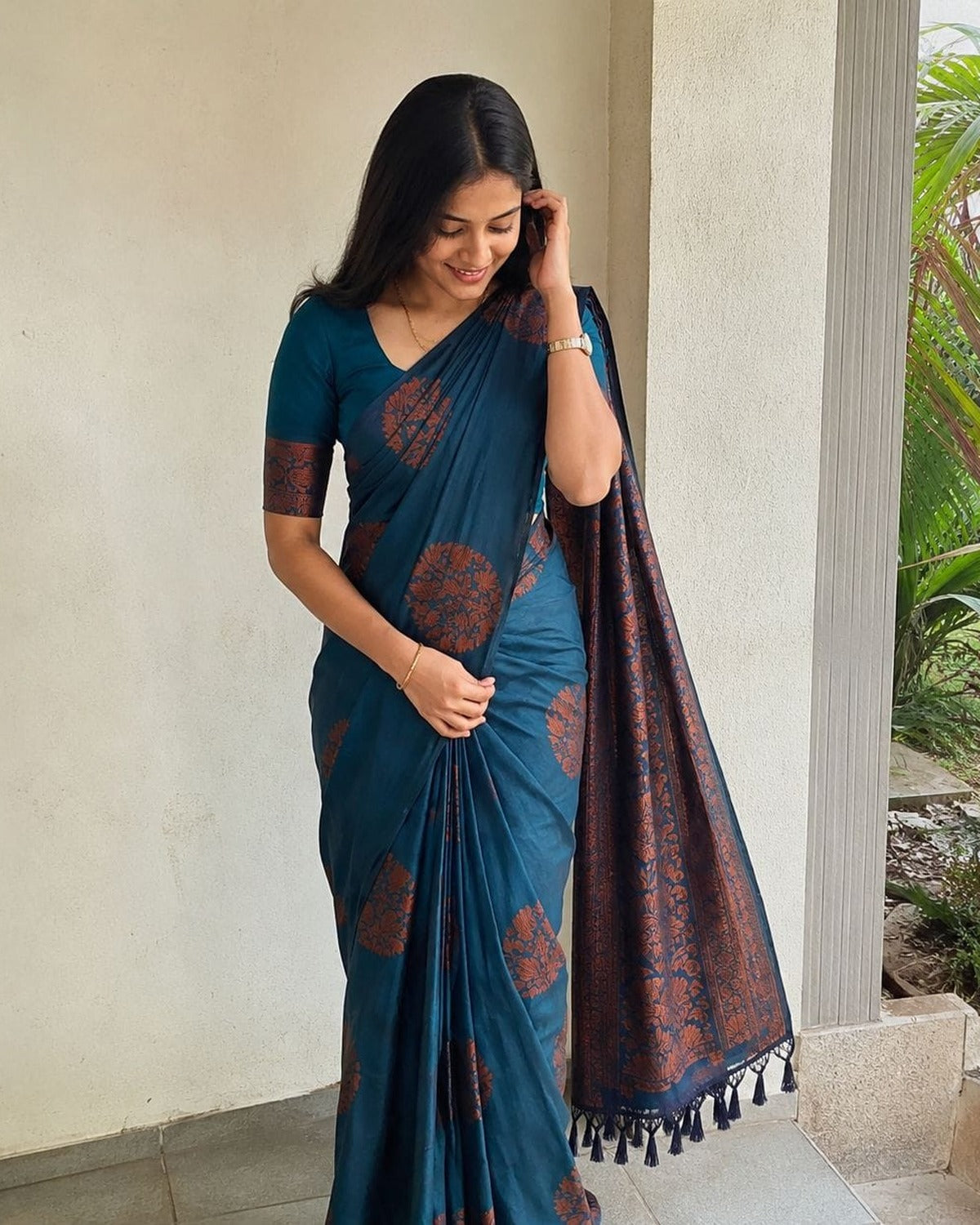 Teal blue Banarasi silk saree with copper floral zari butis and tasselled pallu, worn